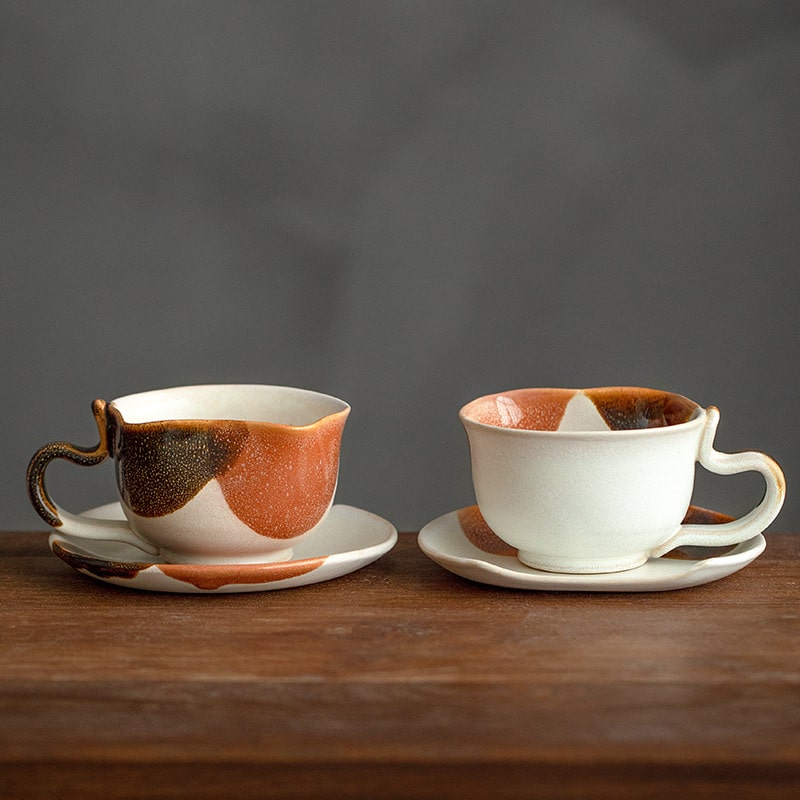 Two ceramic cat-themed coffee cups on a wooden surface