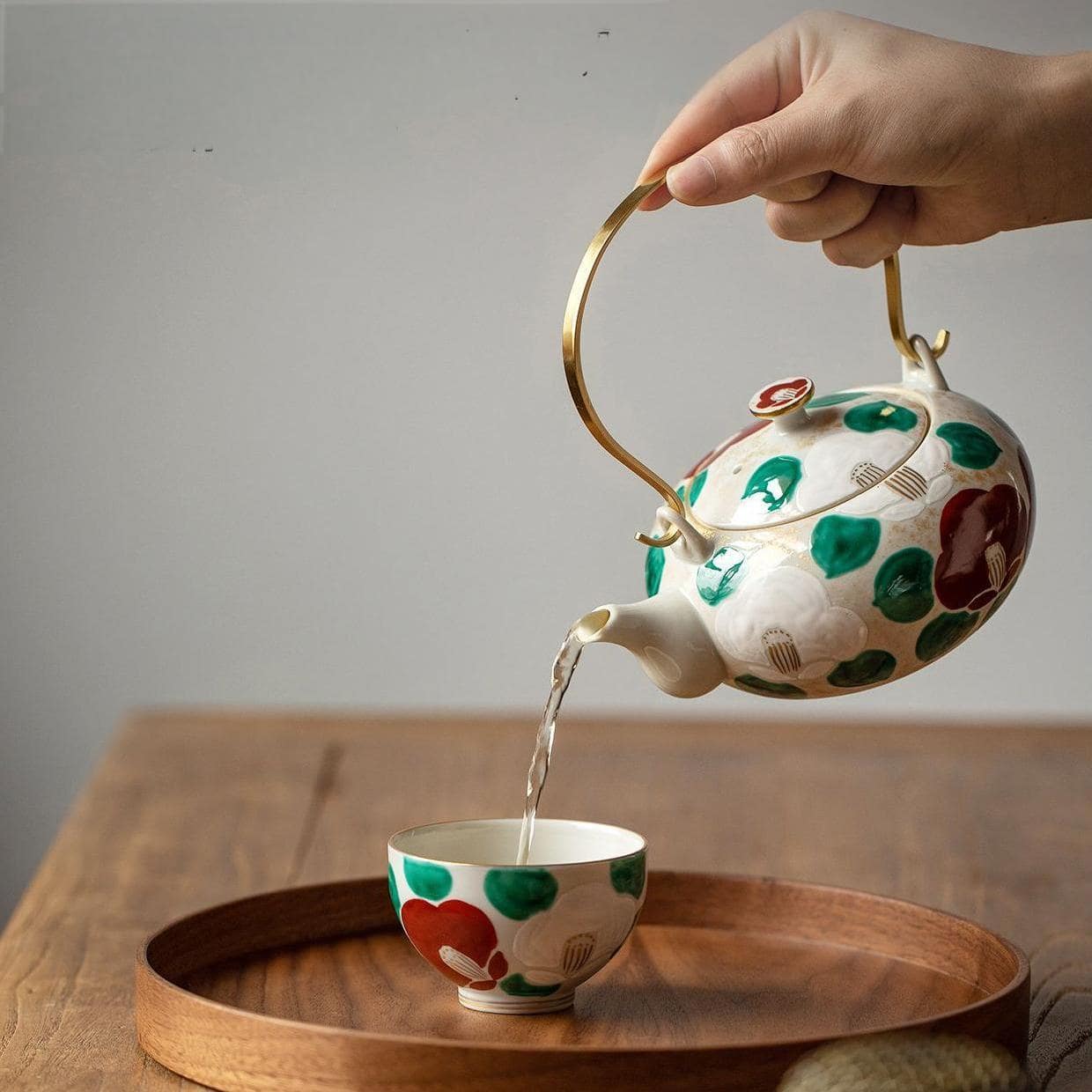 Elegant teapot being used to pour tea into a matching teacup