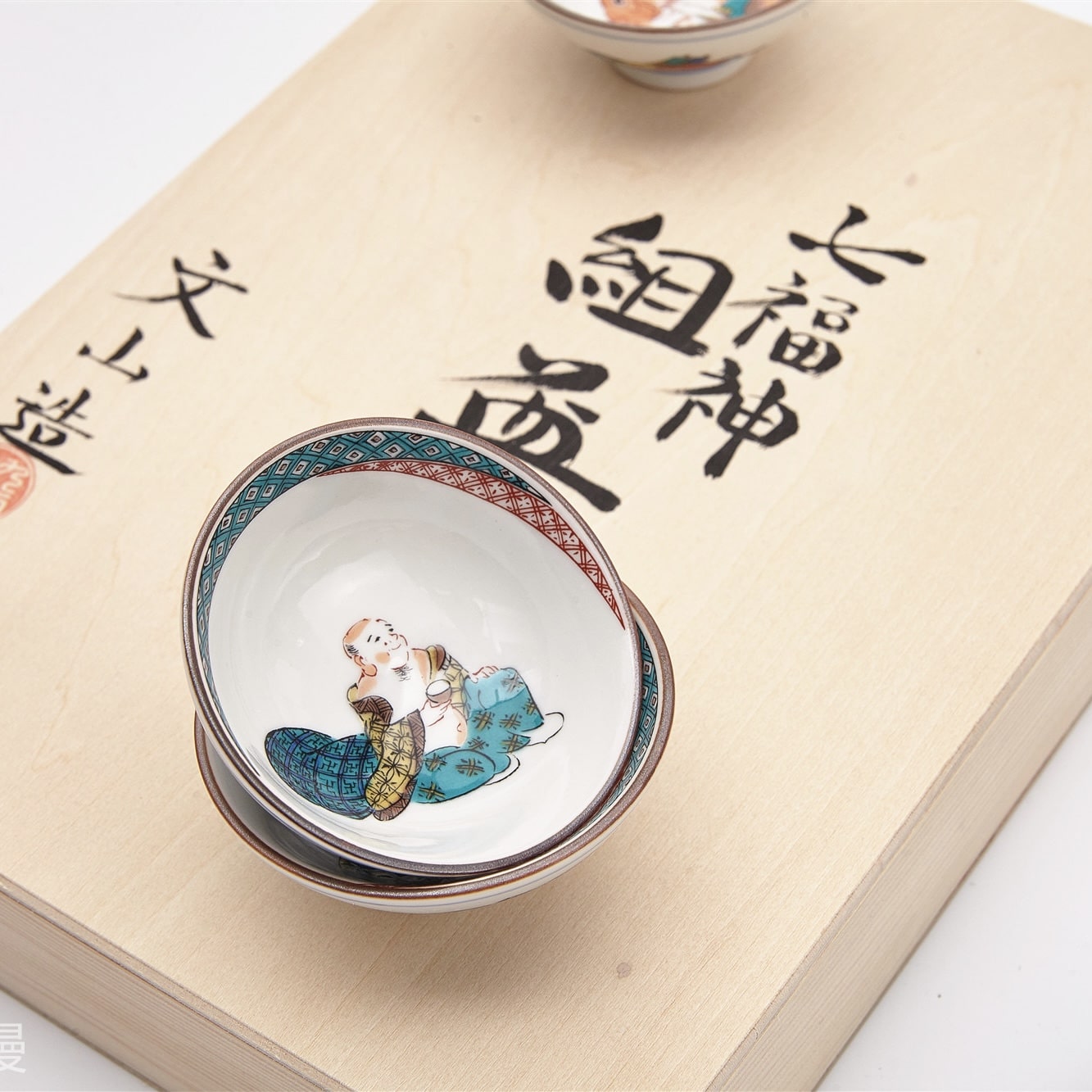 Close-up of vibrant hand-painted designs on Japanese porcelain tea cups.