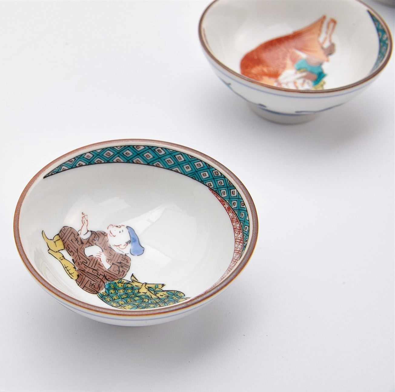 Close-up of vibrant hand-painted designs on Japanese porcelain tea cups.