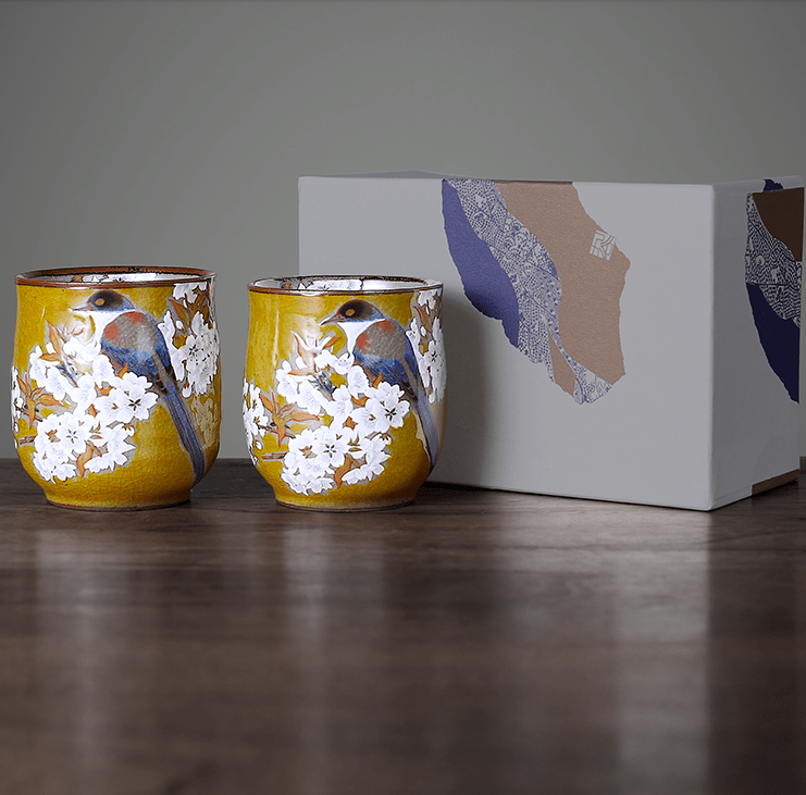 Handcrafted Japanese tea cups with bird and floral designs in a yellow glaze.