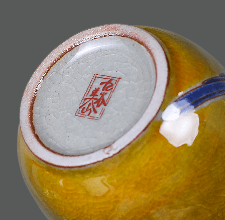 Artistic ceramic tea cups in yellow with detailed bird and floral patterns.