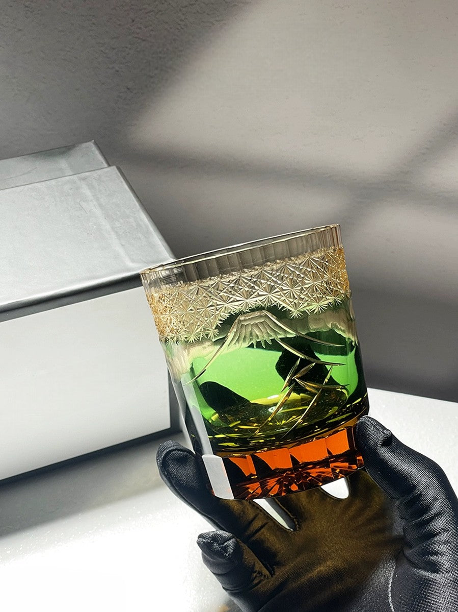 Close-up of Japanese crystal whiskey glass featuring intricate Mount Fuji and palace details in blue and green.