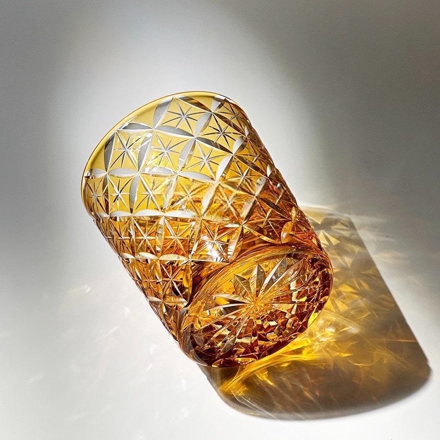 Amber hand-carved "Seven Treasures" crystal whiskey glass with intricate starburst design, perfect for whiskey lovers.