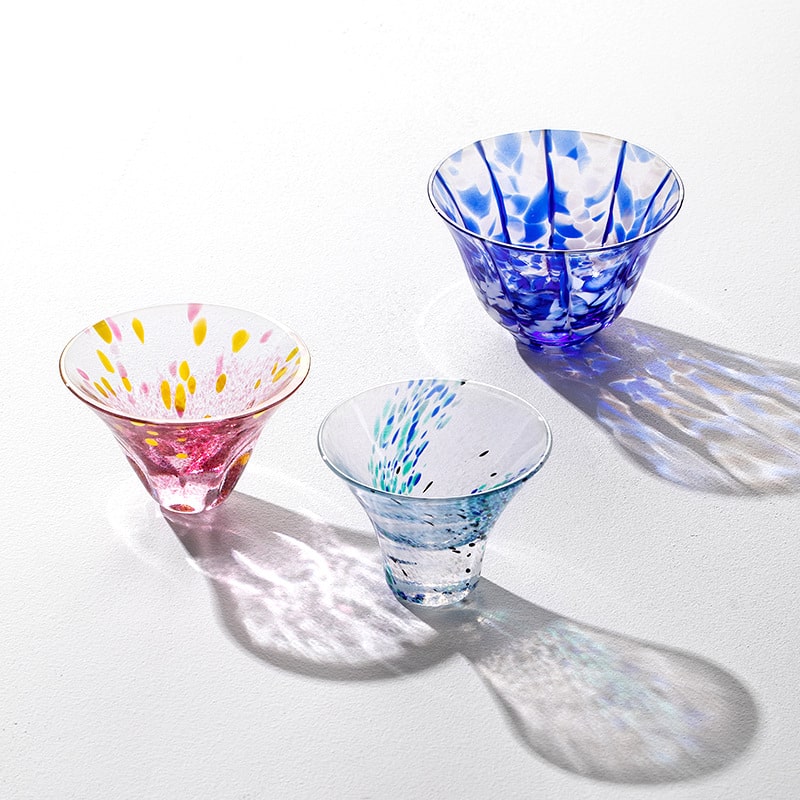 Handcrafted glass cups in pink, blue, and aqua on a white surface