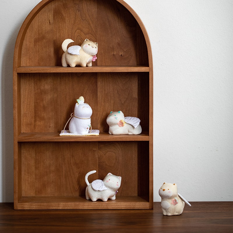 Pastel ceramic lucky cat figurines on a wooden shelf