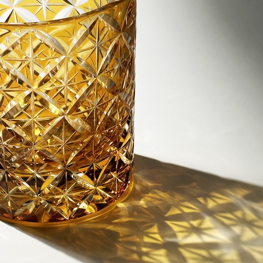 Amber hand-carved "Seven Treasures" crystal whiskey glass with intricate starburst design, perfect for whiskey lovers.