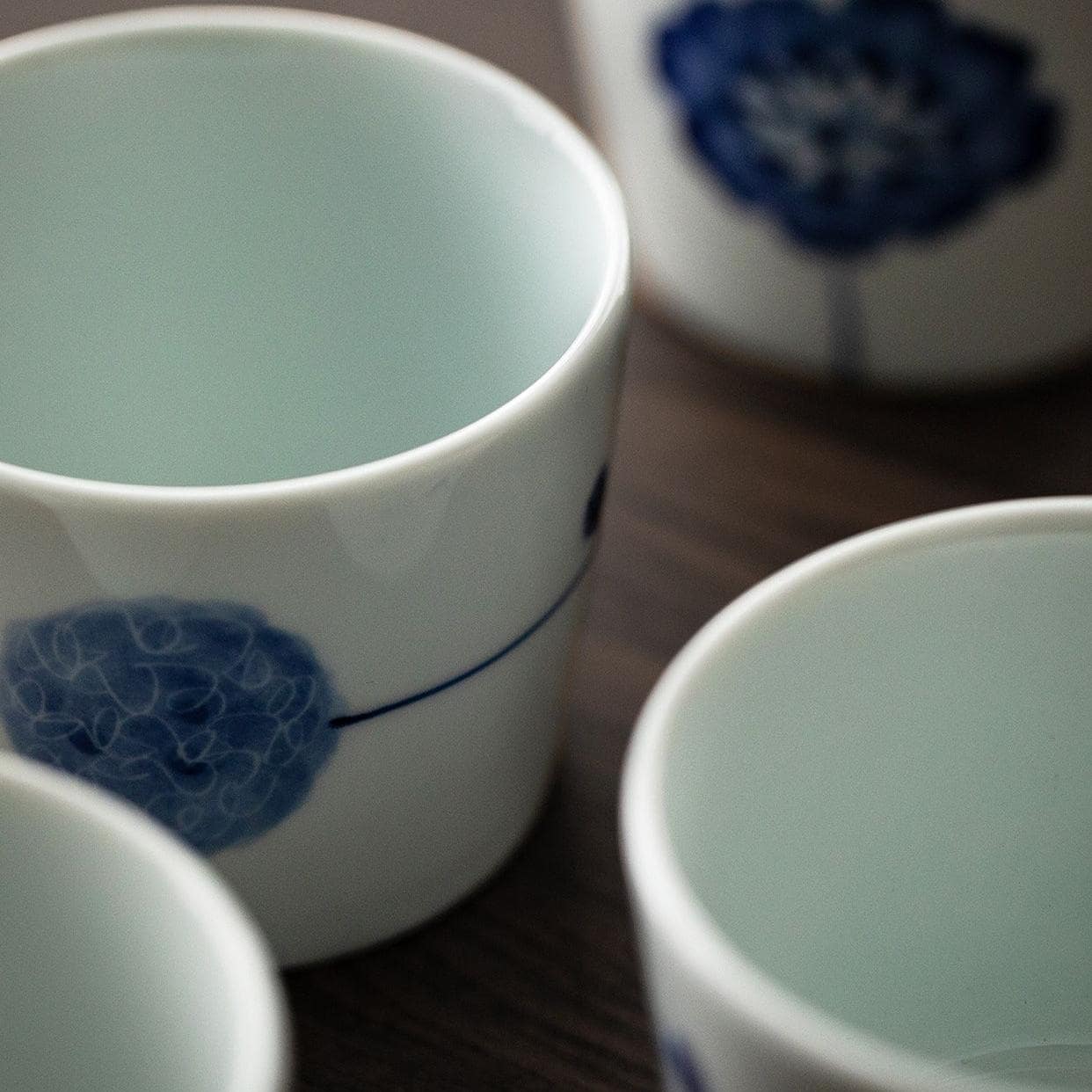 Stack of blue and white porcelain tea cups with nature-inspired designs.