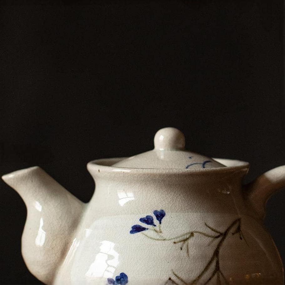 Japanese ice crack ceramic teapot with blue floral pattern on a wooden table.