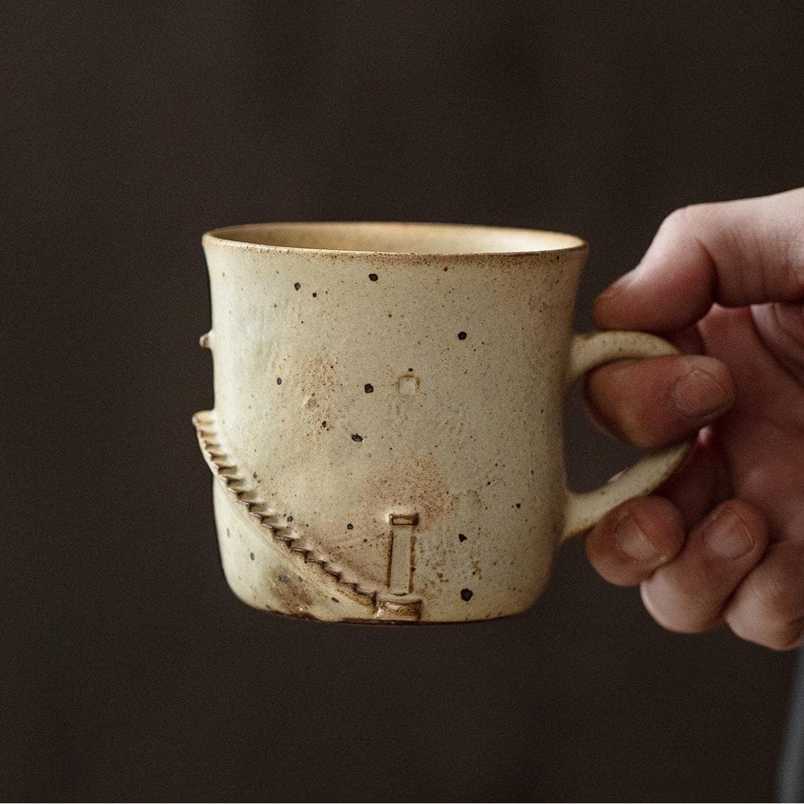 Speckled ceramic tea cup with ergonomic handle.