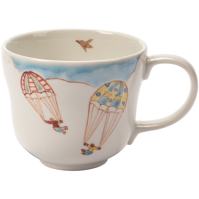 Set of hand-painted ceramic mugs with whimsical designs on a beige backdrop