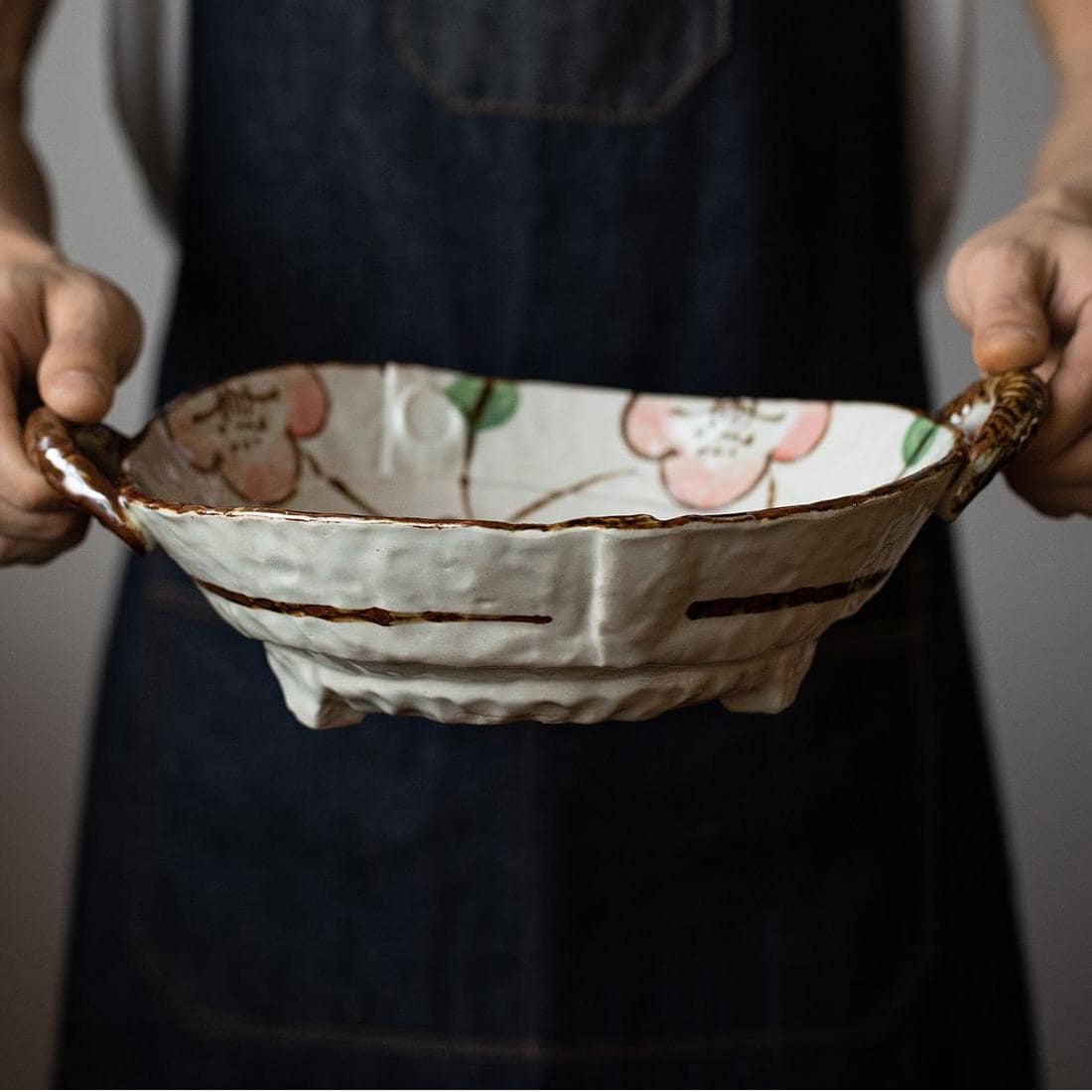 Rustic handcrafted serving bowl with earthy tones and side handles.