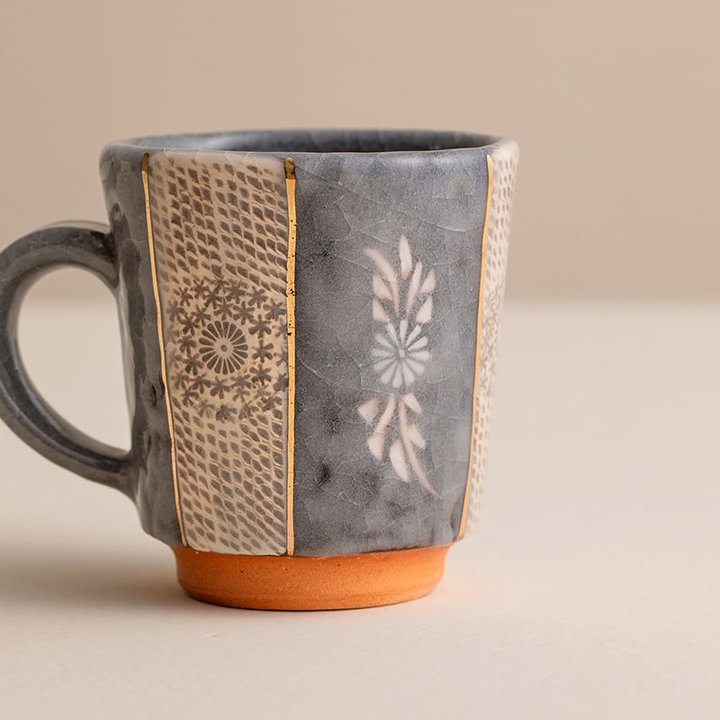 Grey ceramic mug with intricate patterns and a sturdy handle.