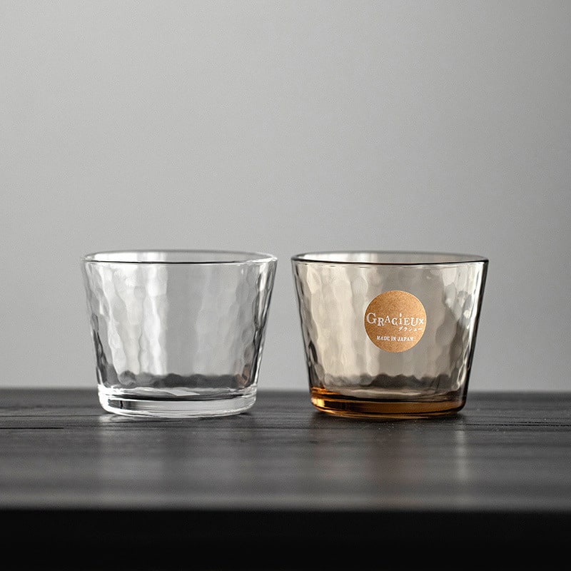 Clear and amber hammered glass cups on a modern table.