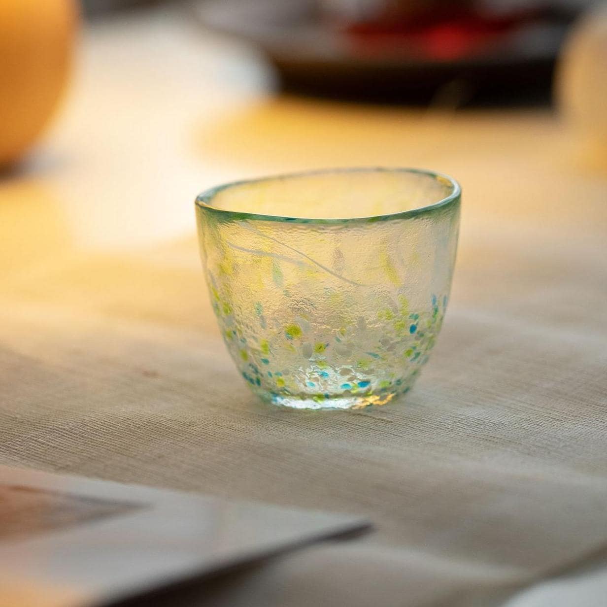 Hand-blown colorful artisan glass cup on white background.