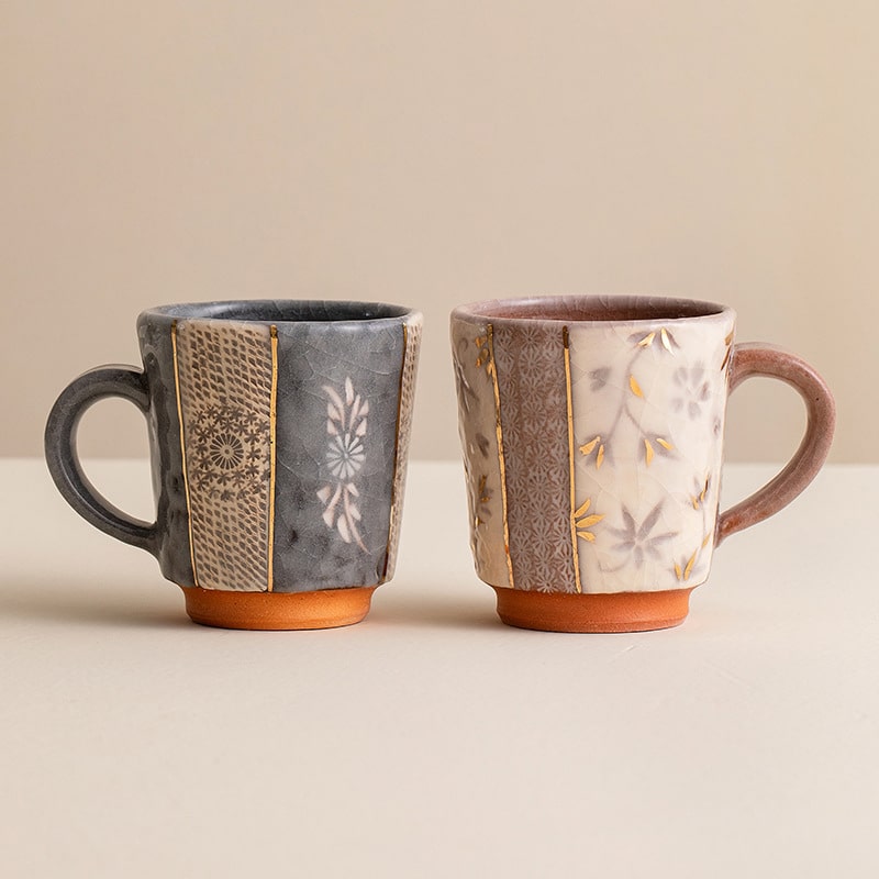 Close-up of textured ceramic mug with gold accents and floral design.