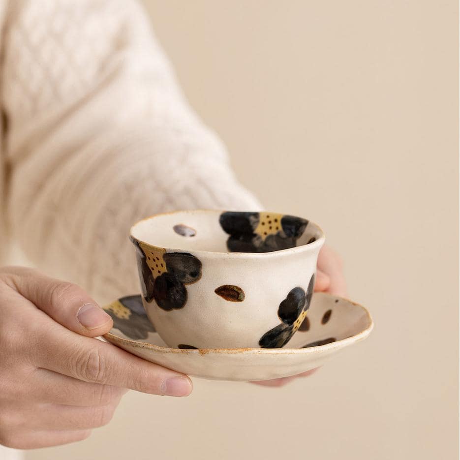 Collection of unique ceramic cup and saucer sets on wooden shelves