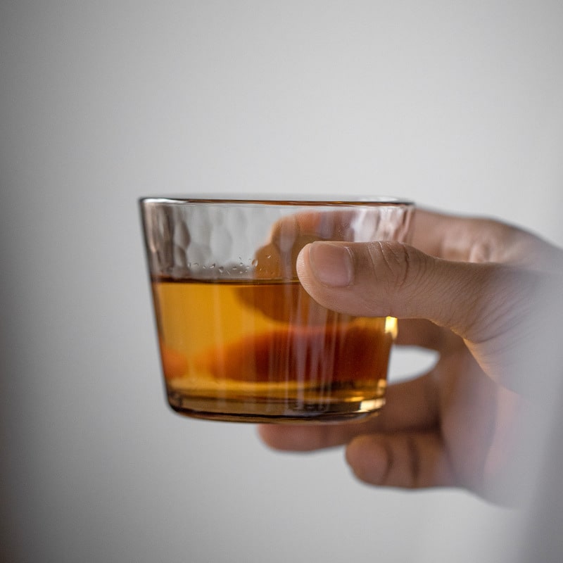 Elegant glass cup on a wooden tray, perfect for beverages.