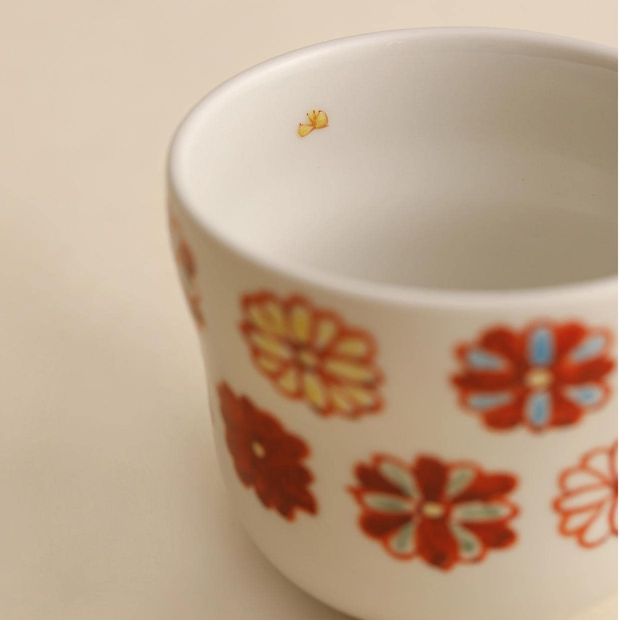 Set of hand-painted ceramic mugs with whimsical designs on a beige backdrop