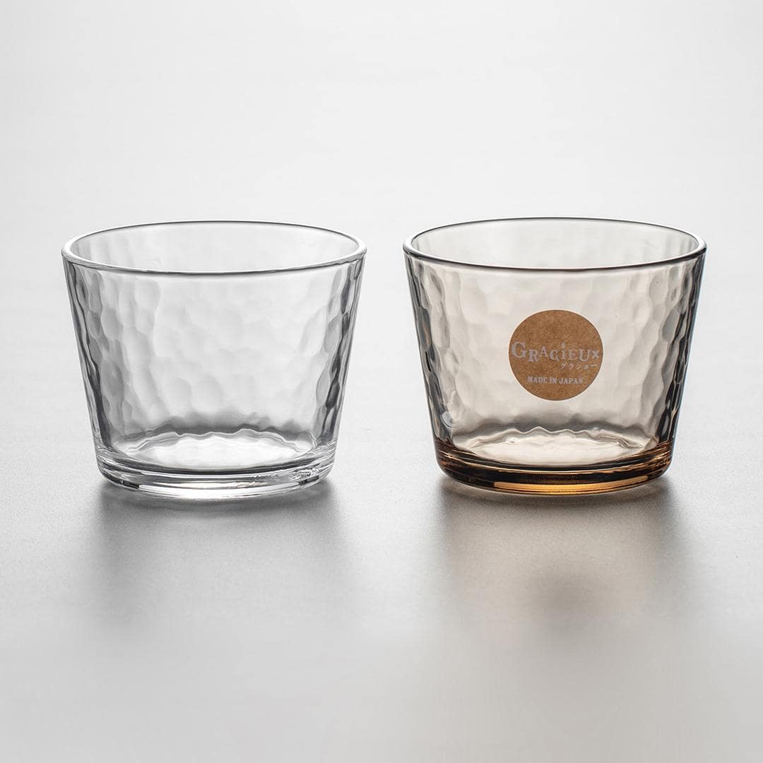 Clear and amber hammered glass cups on a modern table.