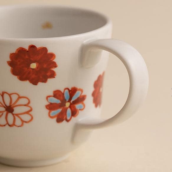 Ceramic mugs with floral and balloon designs on a wooden shelf