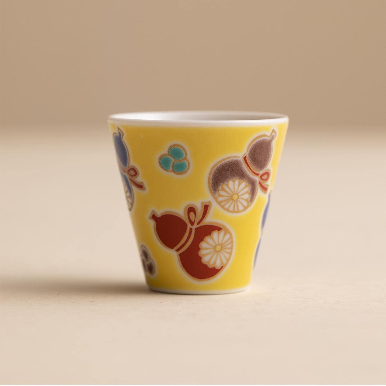 Hand holding a Japanese porcelain cup with intricate details