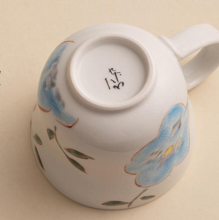 Hand holding a ceramic mug with a blue floral design