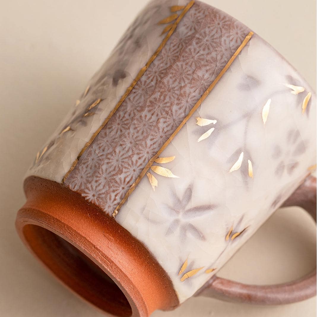 Grey ceramic mug with intricate patterns and a sturdy handle.