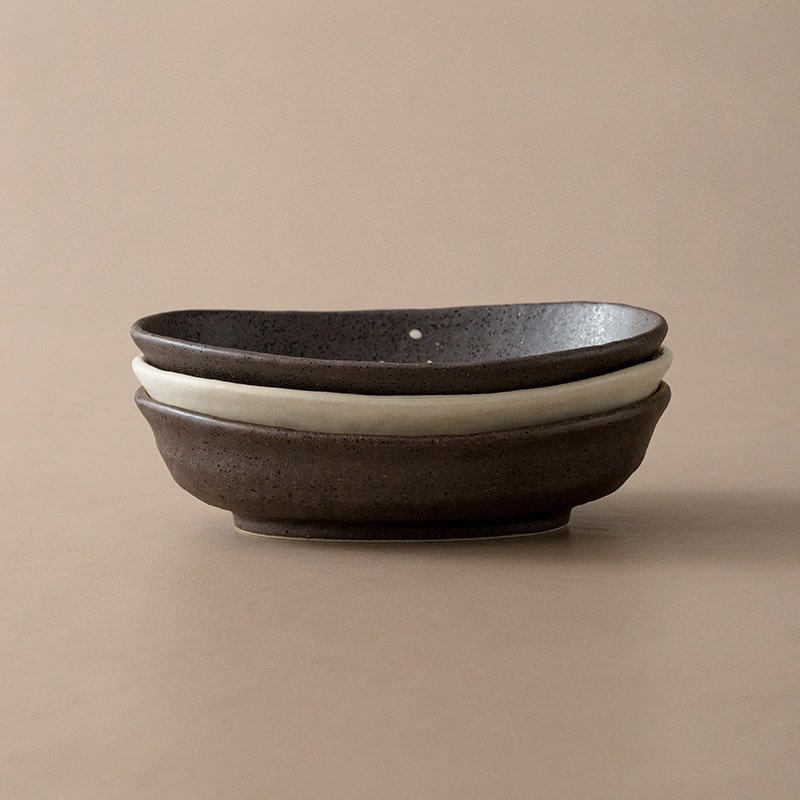 Stack of artisan ceramic plates in black, cream, and brown