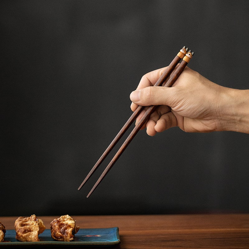 Wooden chopsticks with owl and cat designs on sushi dining table