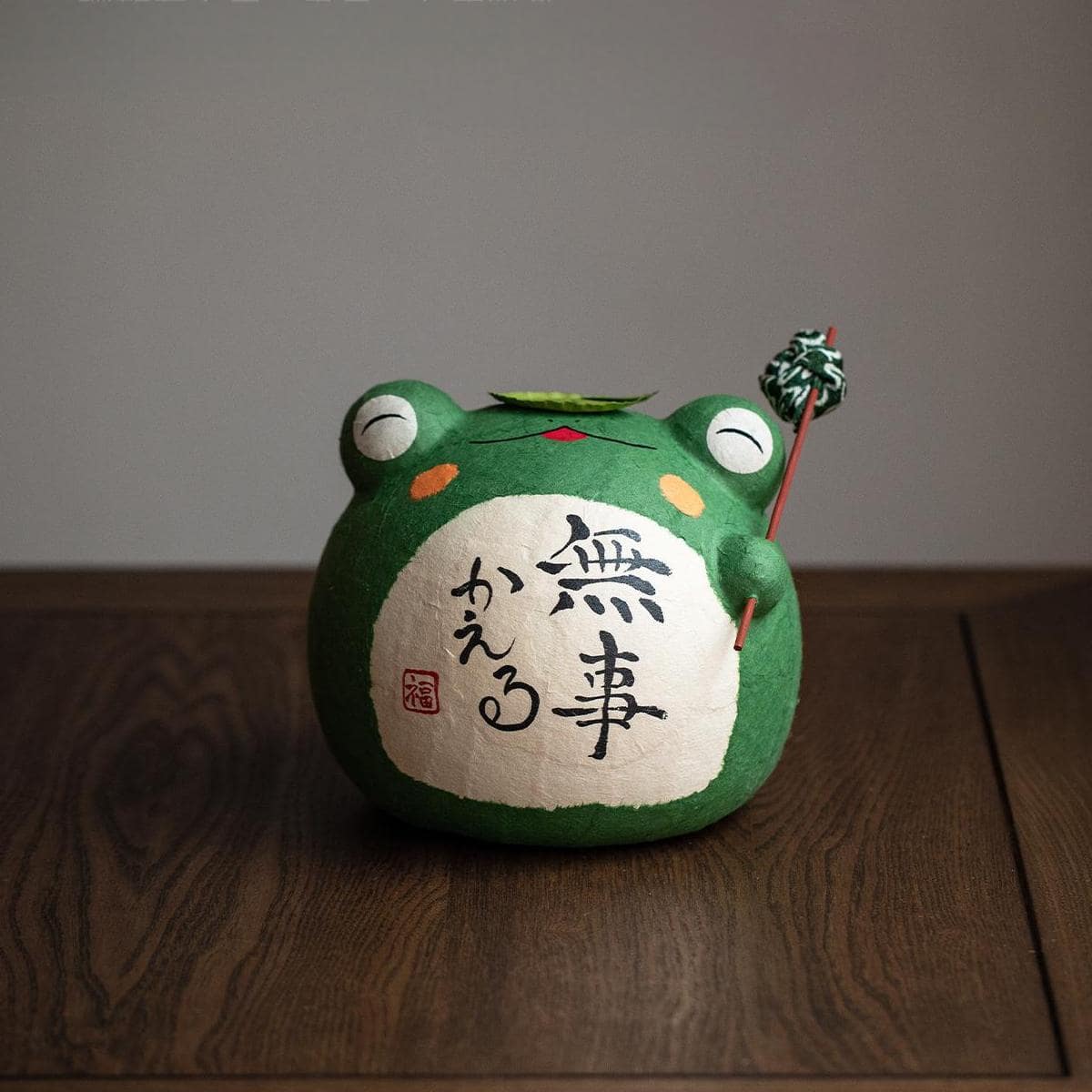 Whimsical green frog ceramic figurine with tiny companion frogs.