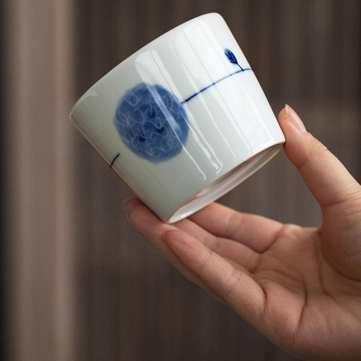 Japanese tea cup being filled with water, showcasing underglaze floral pattern.