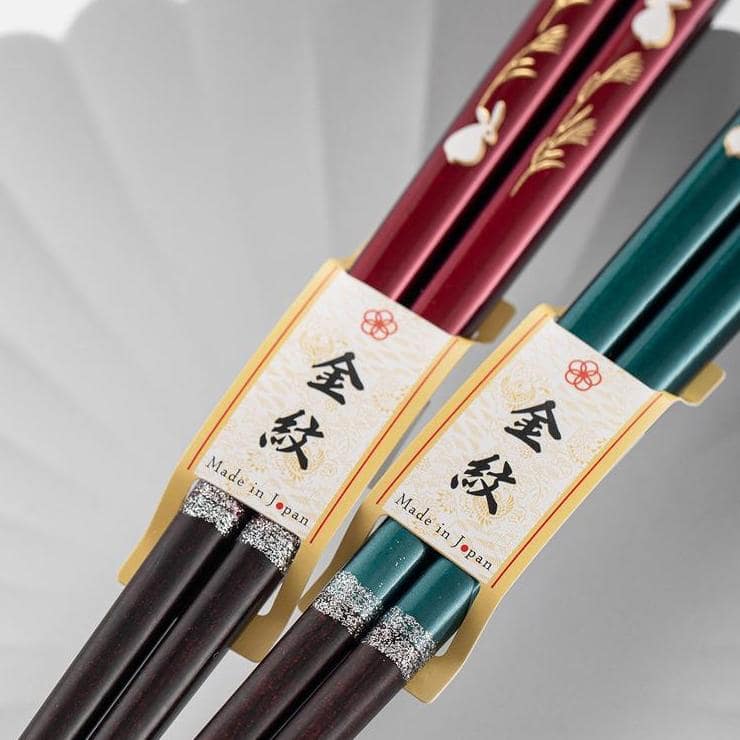 Red and green lacquered chopsticks showcasing intricate motifs.