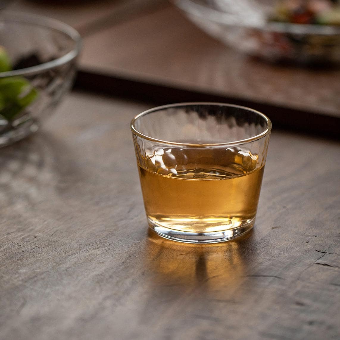 Elegant glass cup on a wooden tray, perfect for beverages.