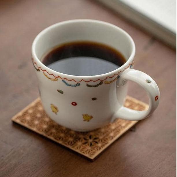 Mug with red floral patterns and tea displayed on a wooden table