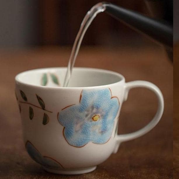 Set of hand-painted ceramic mugs with whimsical designs on a beige backdrop