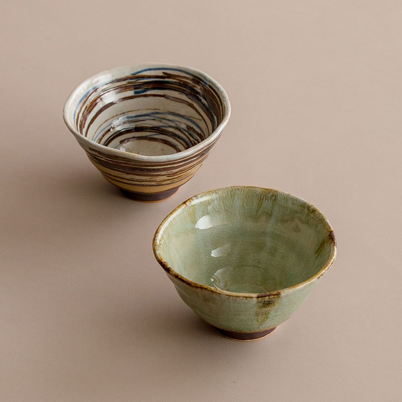 Hand holding a ceramic bowl with chopsticks and rice