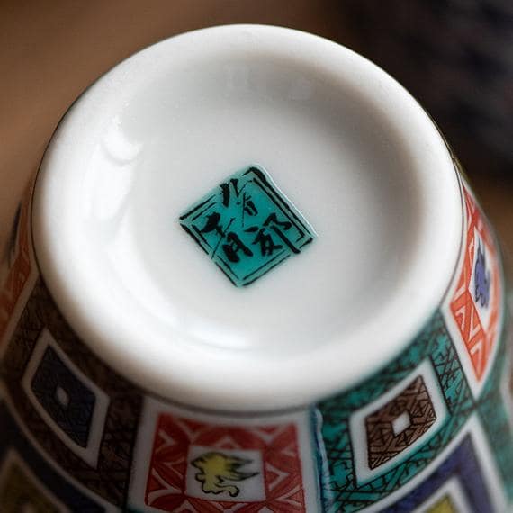 Hand holding a Japanese porcelain cup with intricate details