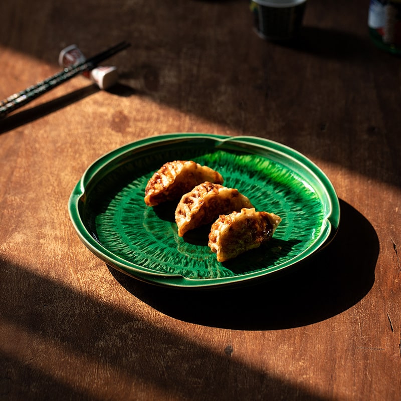 Japanese dessert plate with green glaze on wooden table.