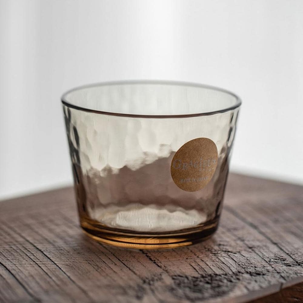 Clear and amber hammered glass cups on a modern table.