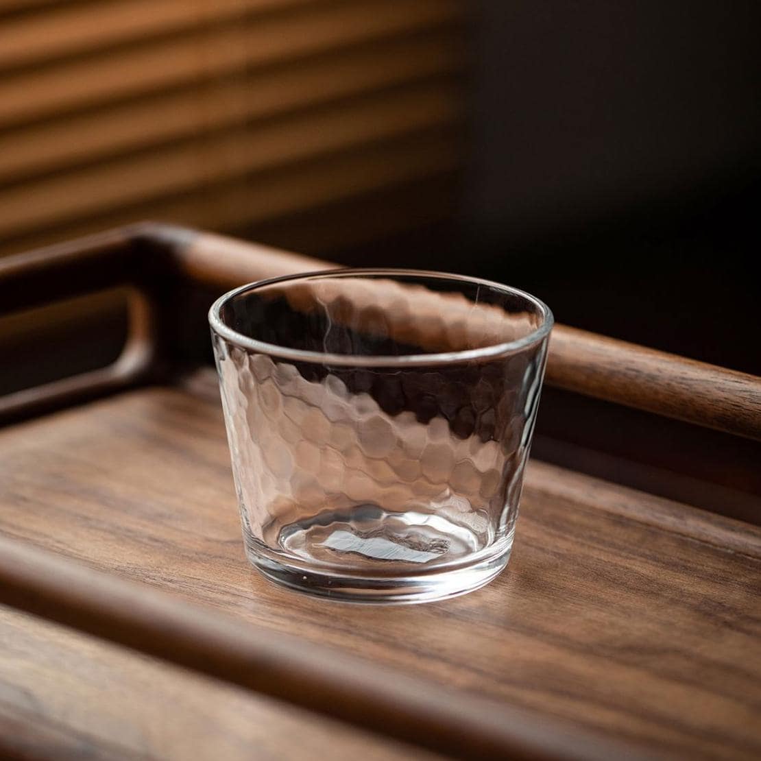 Elegant glass cup on a wooden tray, perfect for beverages.