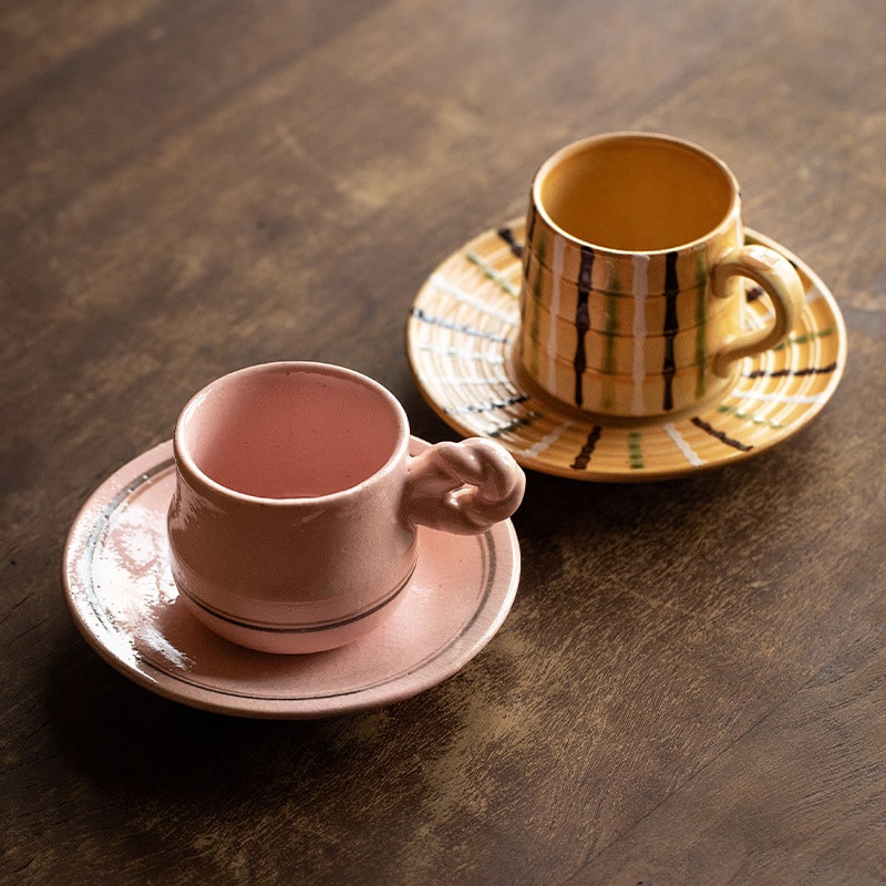 Handcrafted ceramic coffee mug with pink glaze and saucer.