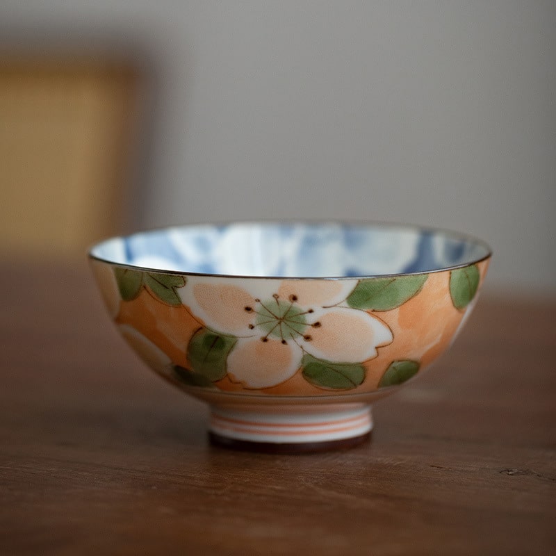 Hand holding a ceramic bowl with rice and chopsticks