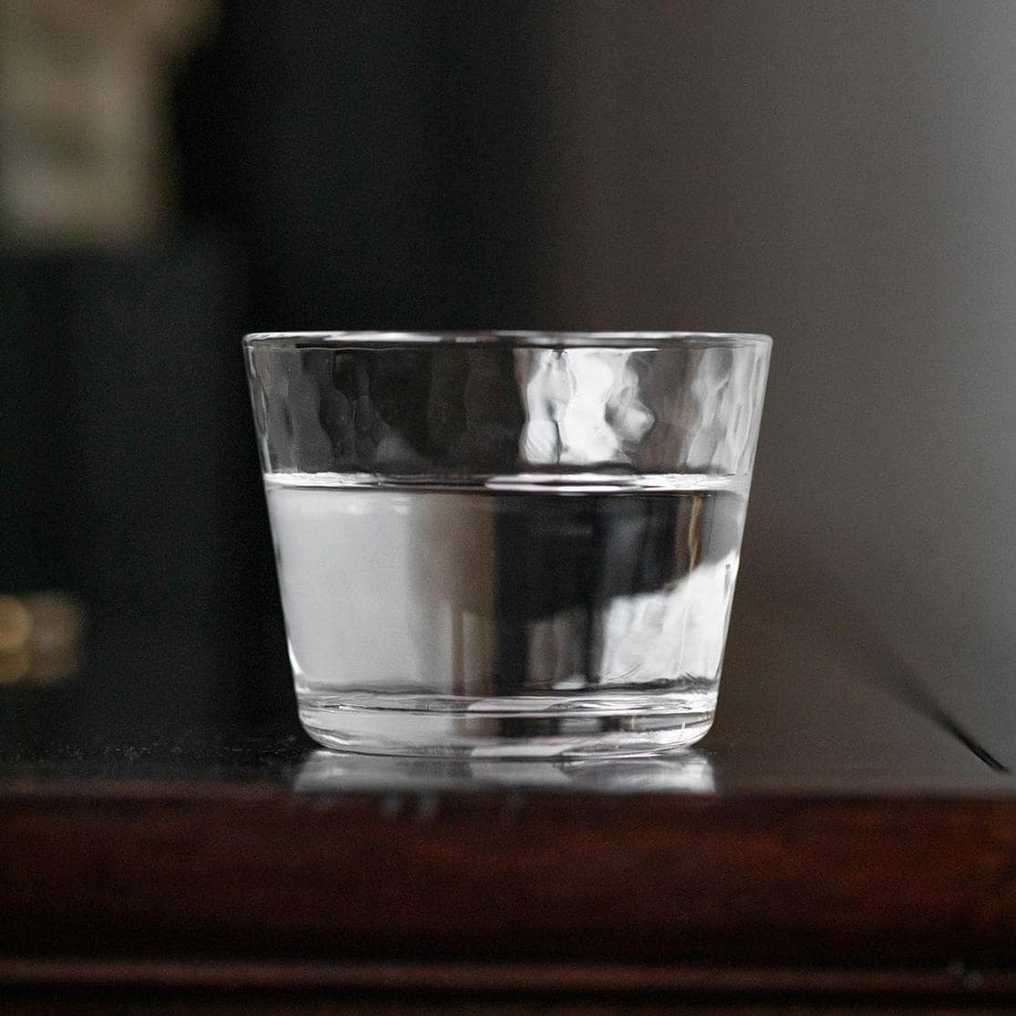 Elegant glass cup on a wooden tray, perfect for beverages.