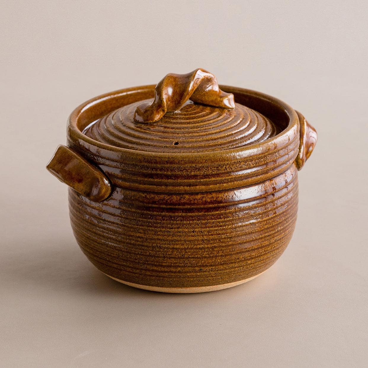 Hand lifting the lid of a black Japanese Shinraku-yaki cooking pot