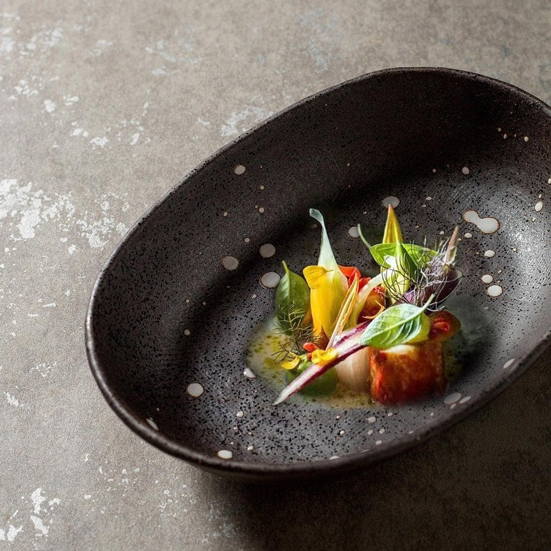 Rustic ceramic plate with splattered black design on table