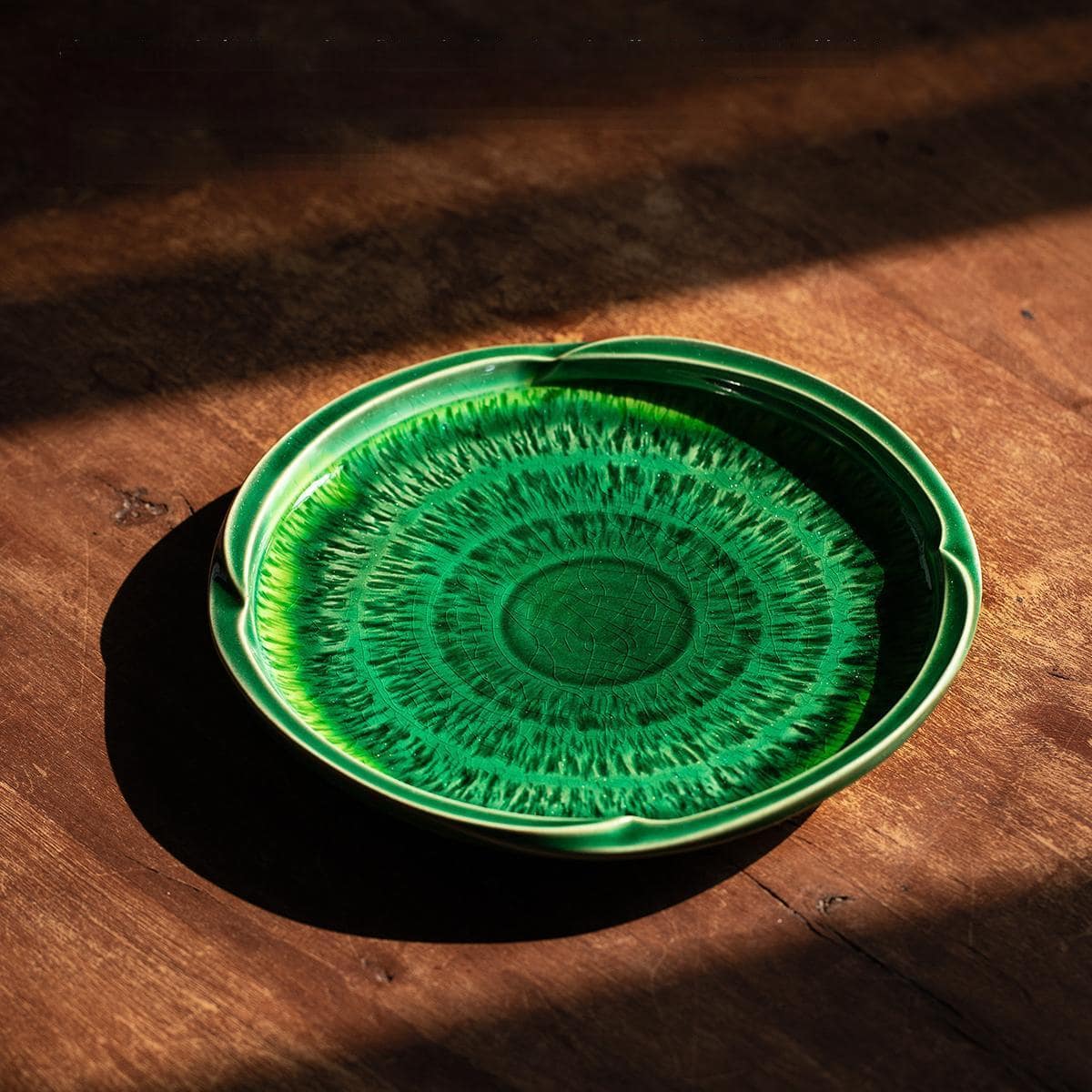 Japanese dessert plate with green glaze on wooden table.