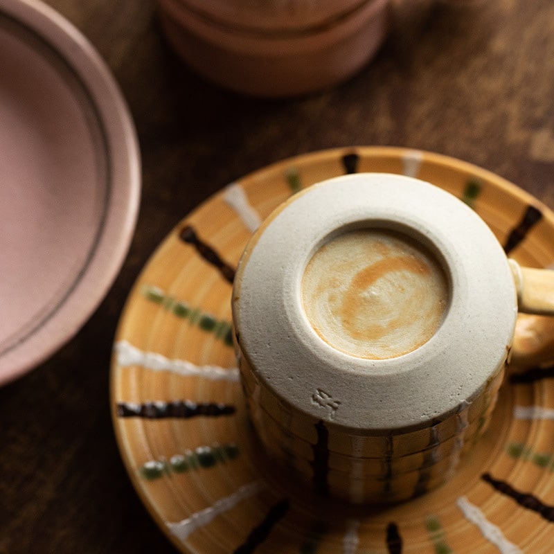 Close-up of handmade ceramic tea mug with unique pink handle.