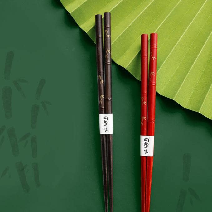 Japanese chopstick set featuring red and brown finishes on a green background.