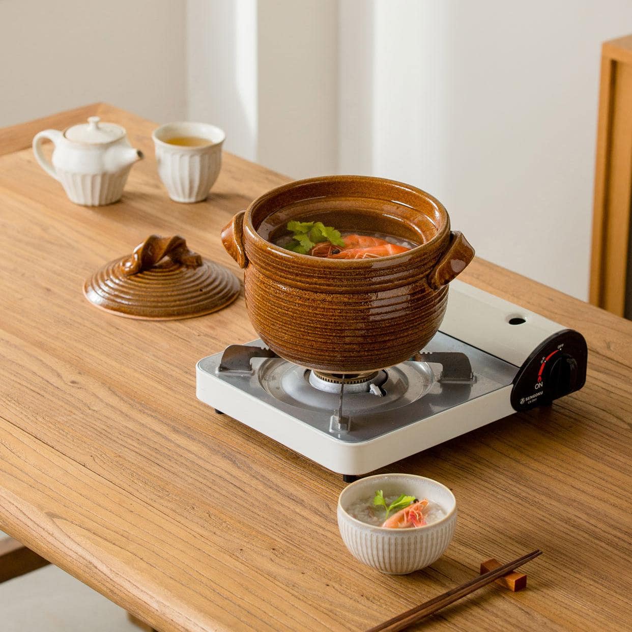 Brown Shinraku-yaki ceramic pot filled with hearty stew on a wooden table